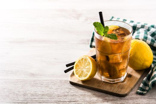 Iced tea drink with lemon in glass and ice on white wooden table