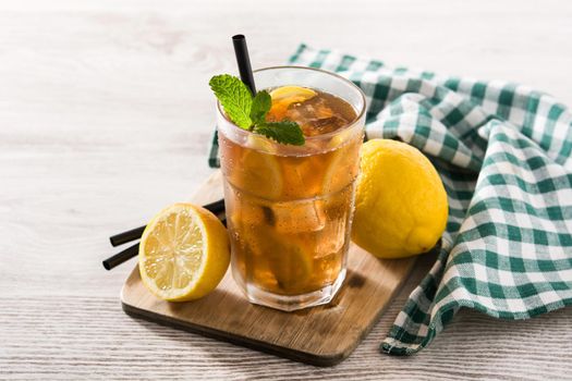 Iced tea drink with lemon in glass and ice on white wooden table