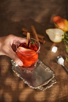 Glass of Cider pear cocktail or lemonade, cinnamon sticks, anise stars on wooden background.