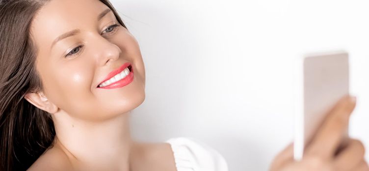 Happy smiling woman with smartphone having video call or taking selfie, portrait on white background. People, technology and communication concept.