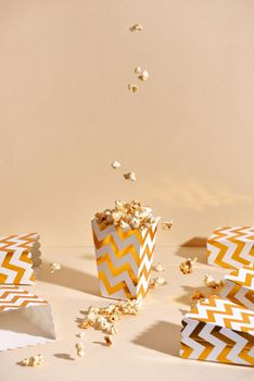 Salty fresh crusty homemade popcorn in golden paper cup in the fashion beige background in a New Year"s interior. selective focus