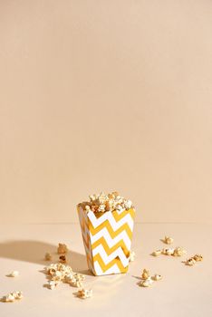 Salty fresh crusty homemade popcorn in golden paper cup in the fashion beige background in a New Year"s interior. selective focus