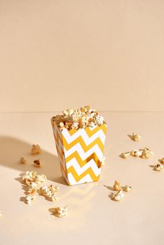 Salty fresh crusty homemade popcorn in golden paper cup in the fashion beige background in a New Year"s interior. selective focus