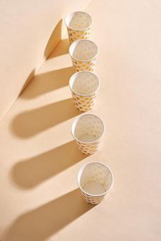 Golden polka dot paper cup isolated on beige background