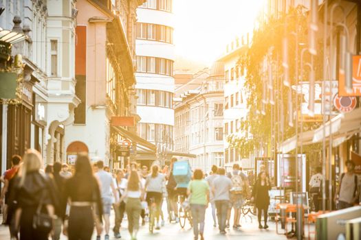 Blurred crowd of people on Copova pedestrian street in Ljubljana at sunset. Urban lifestyle and mobility concept