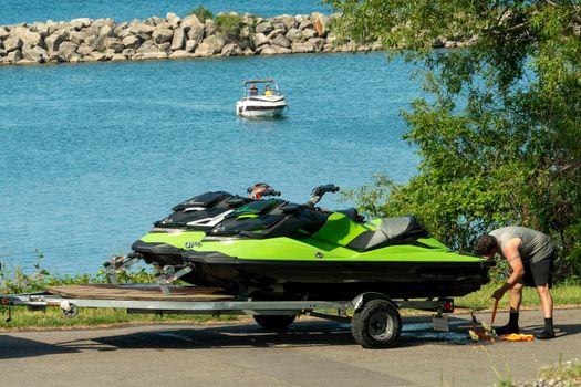 Man loads two jet skis on a car trailer