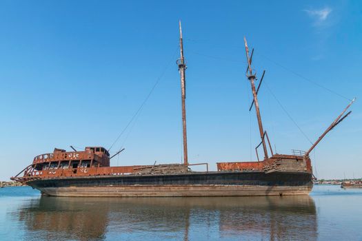 On one of the lakes in Ontario, on the dock, a rusting three-masted ship is living out its last days.