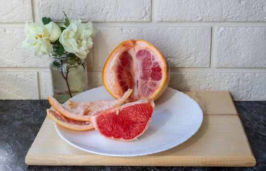 Healthy eating. Fresh healthy grapefruit on a white plate on the kitchen table. Creative concept of minimal food. Grapefruit Citrus Slices.
