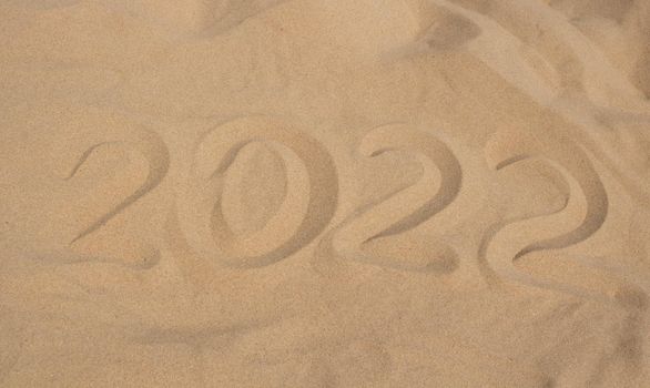 The numbers 2022 in the sand. The concept of the New Year 2022. Summer holidays and sea trips.