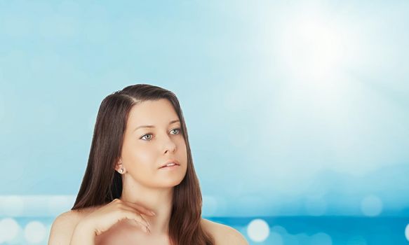 Skincare and sun protection in summer. Portrait of a beautiful young suntanned woman, blue sea and sky on background, beauty, wellness and travel concept.