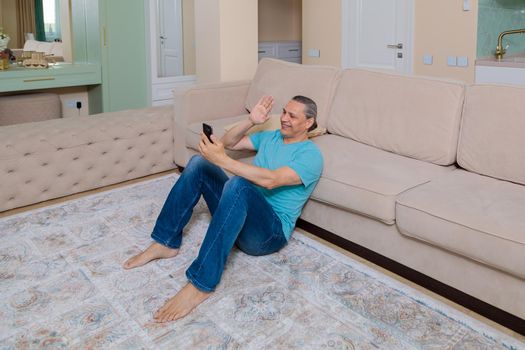 An adult man on the phone talking on video in an apartment.