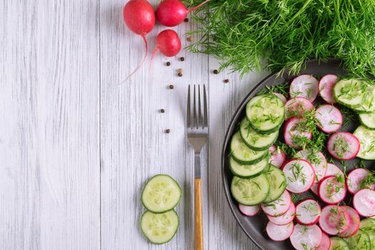 Top view of fresh cucumber and radish salad with dill and vegetable oil. Vegetarian diet. Diesta for weight loss. Healthy eating. Selective focus. Copy space.