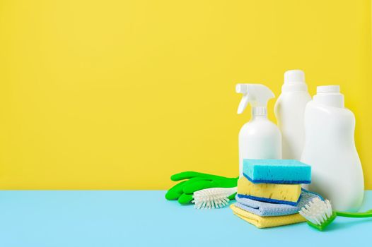 House cleaning products on yellow blue background, copy space. Cleaning service or housekeeping concept with space for text or design