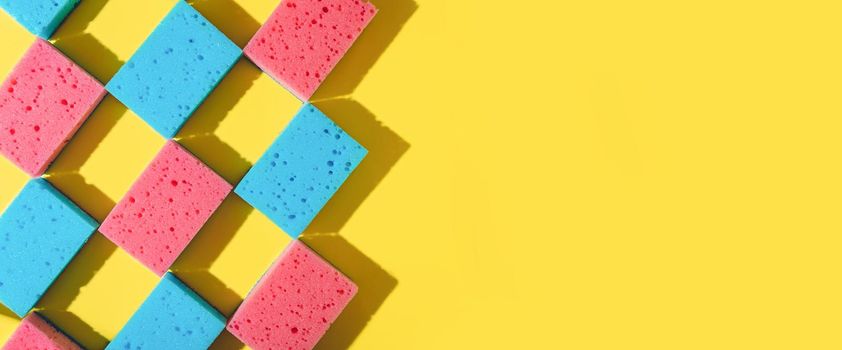 House cleaning sponges on yellow background, copy space. Flat lay or top view. Cleaning service or housekeeping concept with space. Hard shadows in sunlight. Long horizontal banner