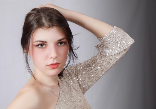 portrait of a young beautiful brunette girl in bright dress in studio on light background