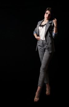 young beautiful girl in a business suit posing standing in the studio on black background