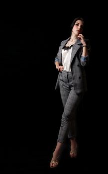 young beautiful girl in a business suit posing standing in the studio on black background