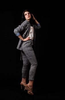 young beautiful girl in a business suit posing standing in the studio on black background