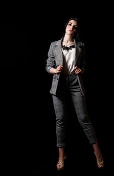 young beautiful girl in a business suit posing standing in the studio on black background