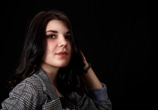 portrait of a young beautiful brunette girl in business suit in studio on black background