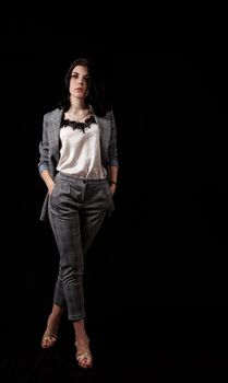 young beautiful girl in a business suit posing standing in the studio on black background