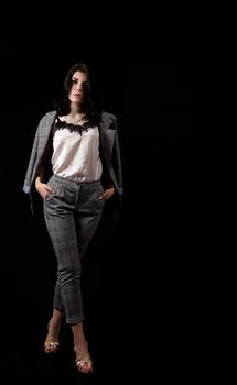 young beautiful girl in a business suit posing standing in the studio on black background