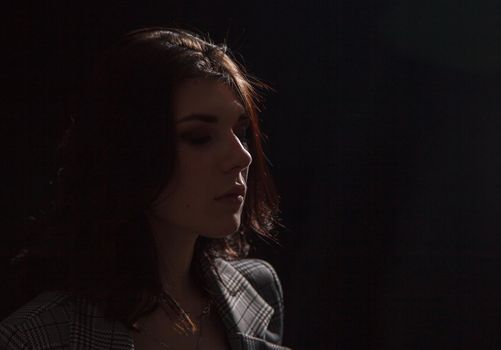 portrait of a young beautiful brunette girl in business suit in studio on black background