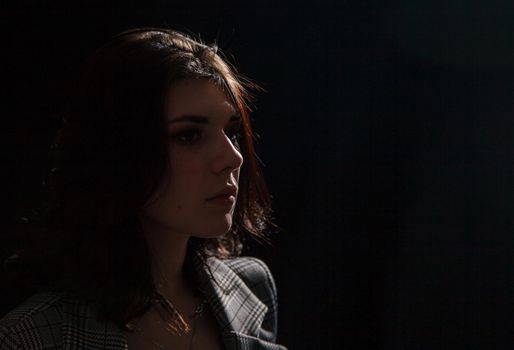 portrait of a young beautiful brunette girl in business suit in studio on black background