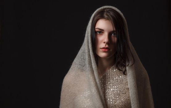 portrait of sad young beautiful girl in bright dress with scarf in studio on black background