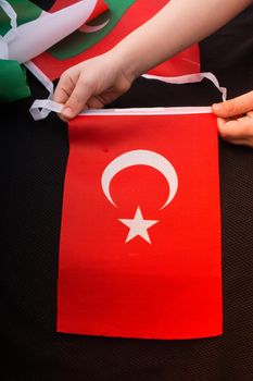 Child hand holding Turkish flag with white star and moon