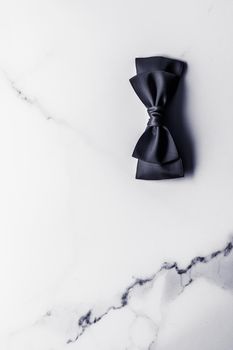 Holiday gift, decoration and sale promotion concept - Black silk ribbon and bow on marble background, flatlay