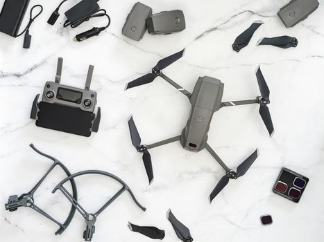Set of folding drone or quadcopter with many accessories, top view or flat lay. Kit of folding drone and equipment for UAV over white marble background.