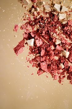 Crushed cosmetics, mineral organic eyeshadow, blush and cosmetic powder isolated on golden background, makeup and beauty banner, flatlay design.