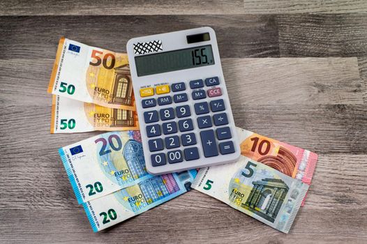different denomination banknotes of euro and calculator on wooden background