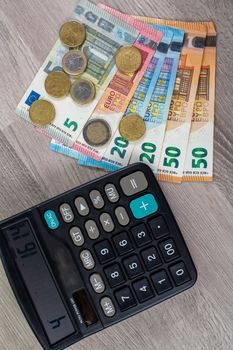 euro money of different denominations and calculator on wooden background