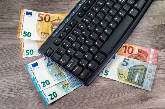 euro banknotes of different denominations and computer keyboard