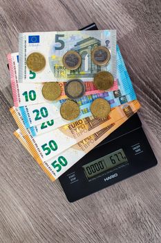 euro money of different denominations on top of a scales on wooden background