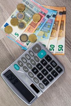 euro money of different denominations and calculator on wooden background