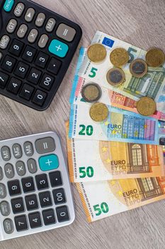 euro money of different denominations and calculators on wooden background