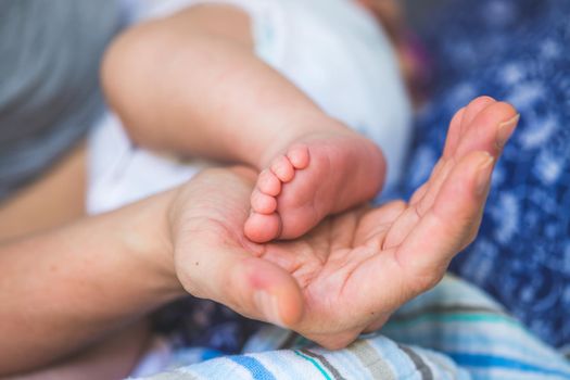 Close up of mother’s hands, holding newborn baby feet.