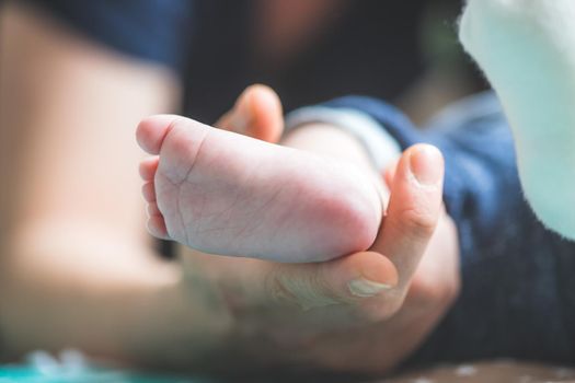 Close up of mother’s hands, holding newborn baby feet.