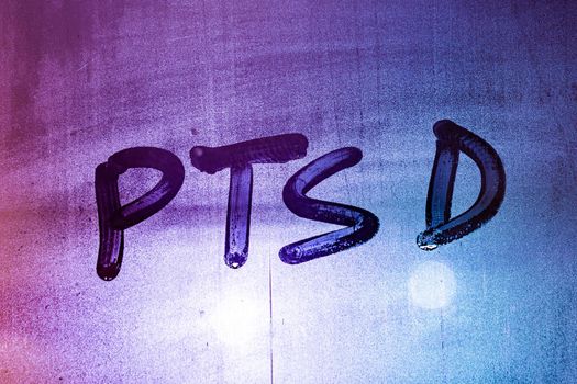 abbreviation ptsd - post traumatic stress disorder - handwritten on night wet window glass, close-up with selective focus