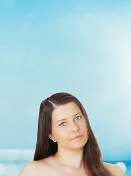 Skincare and sun protection in summer. Portrait of a beautiful young suntanned woman, blue sea and sky on background, beauty, wellness and travel concept.