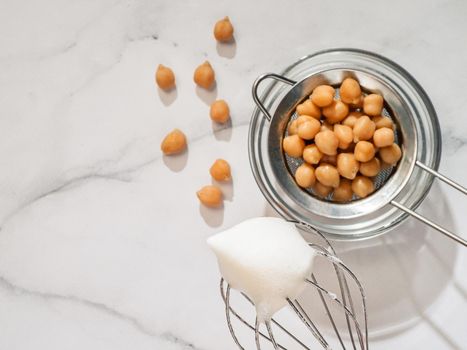 Whipped aquafaba on planetary mixer whisk, vertical. Chickpea water brine aquafaba whipped. Egg replacement in coocking. Vegan concept. Top view or flat lay. Copy space