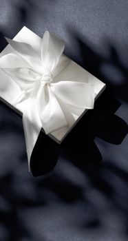 Anniversary celebration, shop sale promotion and luxe surprise concept - Luxury holiday white gift box with silk ribbon and bow on black background, luxe wedding or birthday present