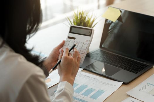 businesswoman working on desk office with using a calculator to calculate the numbers, finance accounting concept