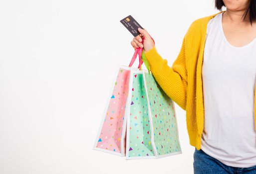 Happy woman hand she wears yellow shirt holding shopping bags multicolor and credit card, young female hold many packets within arms isolated on white background, Black Friday sale concept