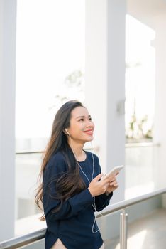 Summer in the city. Pretty young woman with smartphone outdoors.