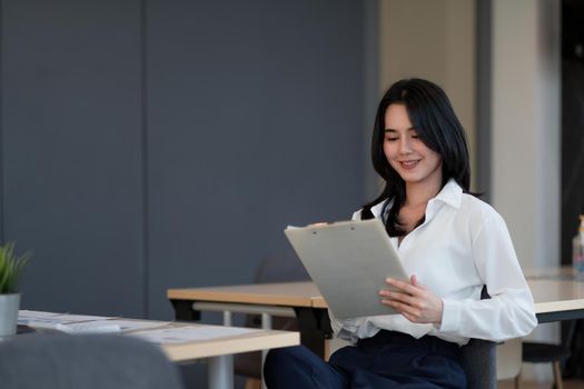 Portrait of successful young Asian businesswoman working with financial report at her office.