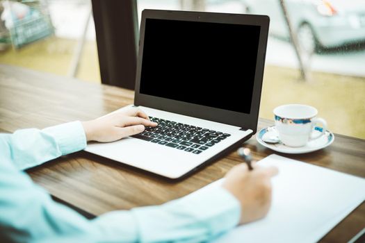 Close-up of business female working with laptop make a note in coffee shop like the background.